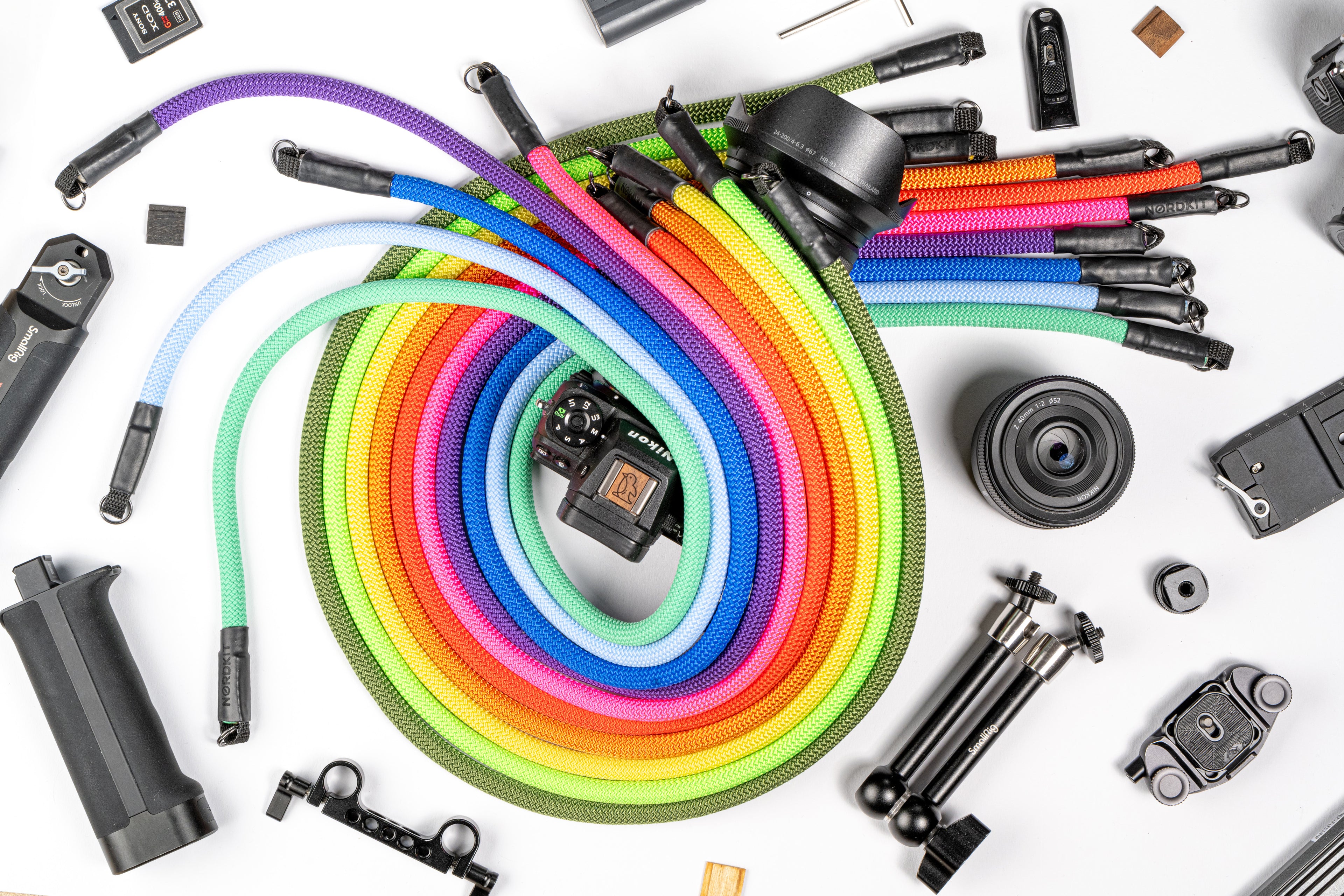 Nahaufnahme von Nordkit Kameragurten mit detaillierter Ansicht der Befestigungen und des Logos, bunt wie ein Regenbogen